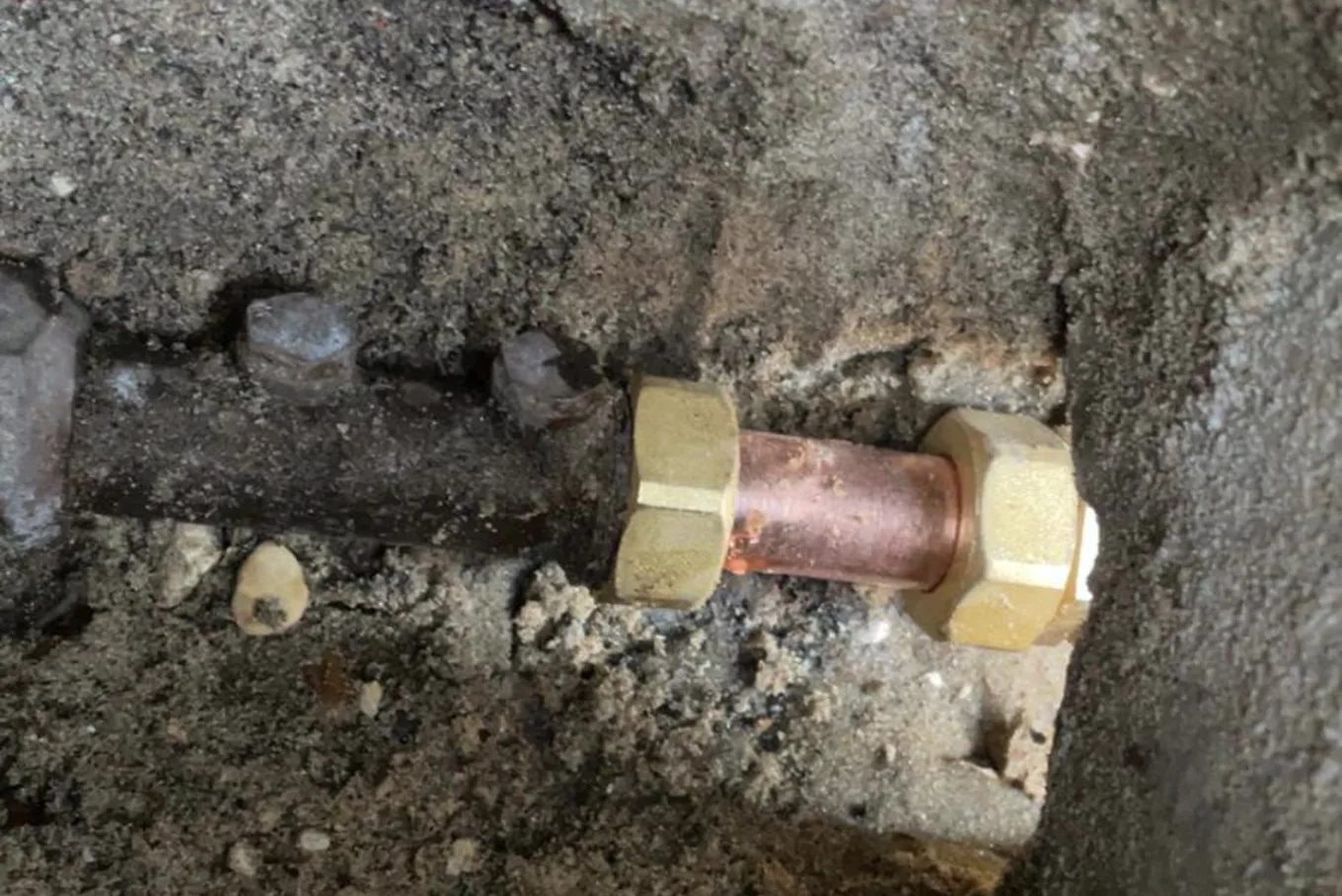 Plombier reprenant une canalisation sous un évier dans un immeuble de Boulogne-Billancourt